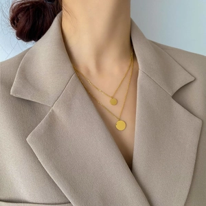 Detail shot of elegant double-layered gold necklace with smooth circular pendant charms