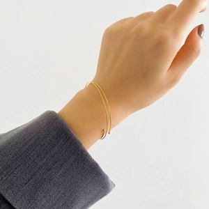 Detailed view of elegant gold minimalist double-line open bangle worn with a suit
