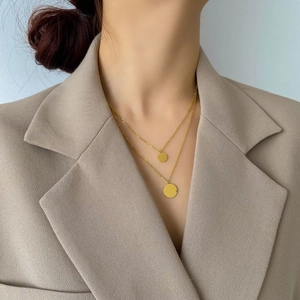Detail view of double-layer gold necklace with round pendants on a female model