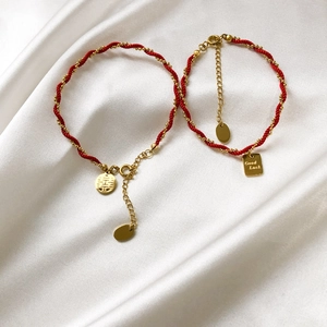Detail of red cord bracelets with golden Good Luck and Xi pendants on white silk