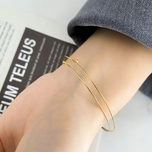 Close-up of a double-layered gold spring bracelet worn with a professional grey blazer