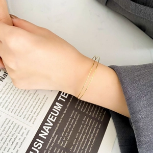 Detailed view of minimalist gold double-line spring bracelet worn on a model's wrist