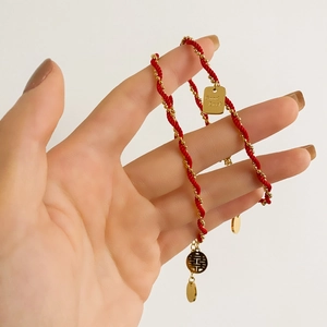Detailed shot of red cord bracelet with gold Good Luck charms and Double Happiness pendant