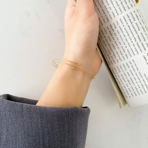 Minimalist double-layered gold spring bracelet with bead accents on female wrist