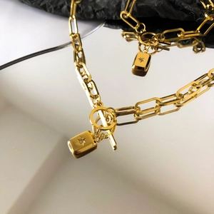 Détail du collier à maillons trombone dorés avec pendentif étoile gravé et fermoir à bascule