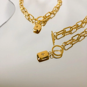 Détail macro d'une chaîne trombone dorée avec fermoir à bascule et pendentif étoile