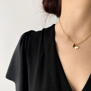Détail d'un pendentif papillon doré à double couche sur une chaîne torsadée