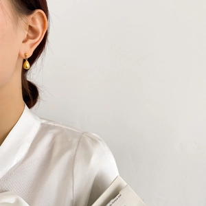 Close-up of a model wearing minimalist golden teardrop earrings with a polished finish