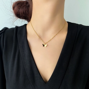 Détail d'un pendentif papillon doré poli sur une chaîne torsadée porté par un mannequin