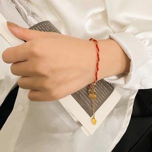 Close-up of red braided rope bracelet with gold beads and double happiness pendant