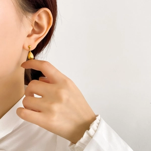 Close-up of polished gold teardrop earrings worn by model for a minimalist fashion look