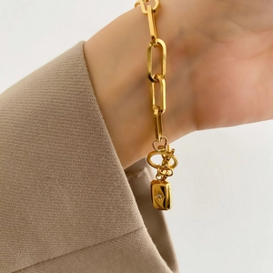 Détail d'un bracelet gourmette dorée avec fermoir OT et pendentif étoile sur le poignet
