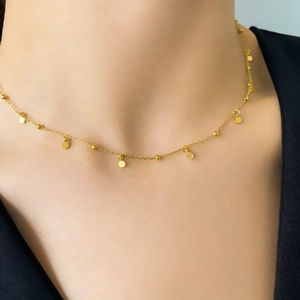 Close-up of minimalist gold titanium steel necklace with small round disc pendants