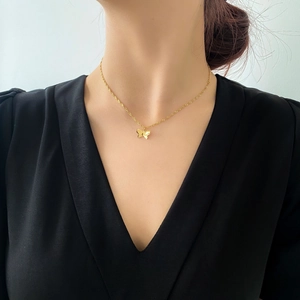 Gros plan d'un collier pendentif papillon doré minimaliste sur le décolleté d'un mannequin