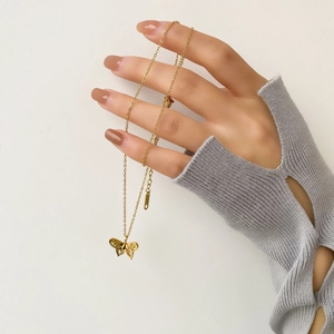 Gold plated hollow butterfly necklace with delicate chain shown against a clean white wall