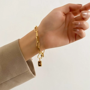 Détail du bracelet chaîne dorée épaisse avec pendentif étoile rectangulaire au poignet