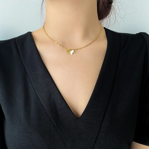 Gros plan d'un pendentif papillon doré avec chaîne torsadée sur un mannequin