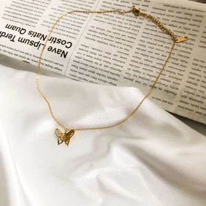 Close-up of gold hollow butterfly pendant with K18 engraved tag and delicate chain