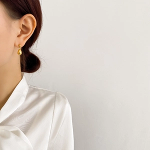 Close-up of elegant gold teardrop earrings worn by a model for a minimalist fashion look