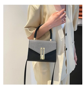 Detail of grey fabric and black leather contrast handbag with gold hardware