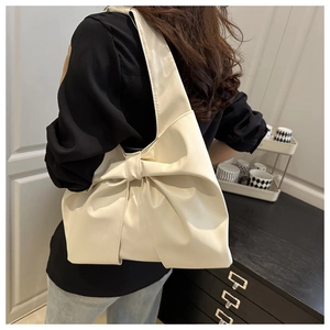 Side view of cream hobo bag with large bow detail worn by model on shoulder