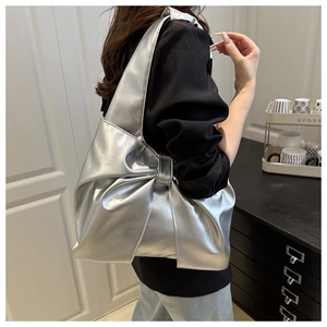 Detailed side view of silver bow-shaped tote bag with metallic finish on shoulder