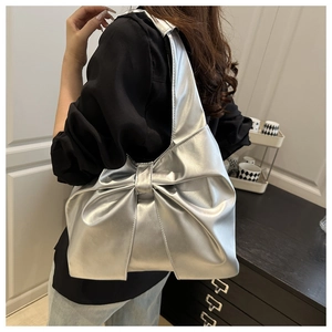 Detail of silver metallic PU shoulder bag featuring a large decorative bow design