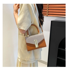 Detail of vintage brown shoulder bag showing textured fabric flap and gold metal buckle