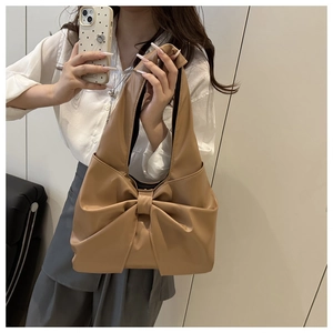 Close-up of khaki underarm bag featuring a large bow design and soft pleated texture