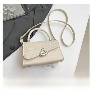 Dettaglio della borsa beige con patta a motivo a V e fibbia in metallo a forma di cuore