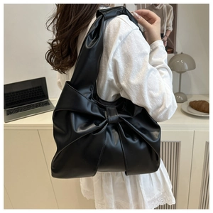 Close-up of elegant black PU leather tote bag featuring a large decorative bow design