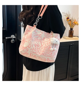 Detail of white graffiti canvas tote bag with pink leather strap and plush cloud charm