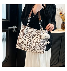 Close-up of doodle canvas tote with leather chain straps and plush cloud charm