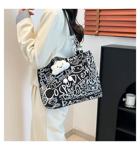 Close-up of black graffiti tote bag with white lettering, metal chain, and plush cloud charm