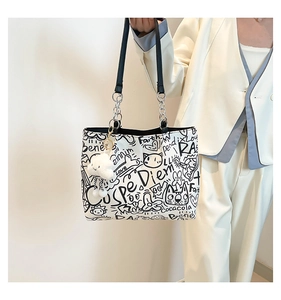 Detail of graffiti canvas tote with metal chain straps and plush cloud charm accessory