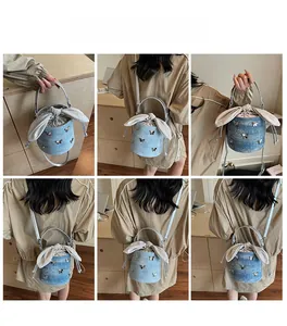 Detail view of denim bucket bag with silver butterfly and rabbit ear ribbon decoration