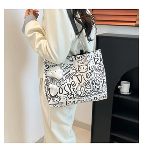 Detail of white graffiti canvas tote with cloud charm and chain strap on model
