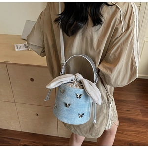 Detailed macro view of light blue denim bucket bag with silver butterfly metal studs