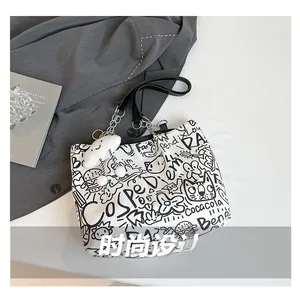 Detail of white graffiti canvas tote with metal chain and plush cloud pendant charm