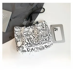 Detail of white graffiti tote bag with black cartoon prints and silver chain strap