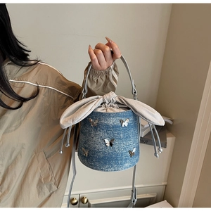 Detail view of denim bucket bag with silver butterfly charms and rabbit ear drawstring
