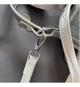 Macro detail of the polished silver swivel clasp and gray strap on denim bucket bag