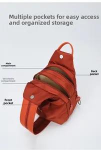 Detail view of orange nylon crossbody bag showing main and side zipper compartments