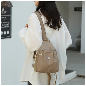 Close-up of khaki oxford mini backpack shown from the side on a model's shoulder