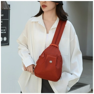 Close-up of caramel nylon chest bag featuring front zipper pocket and metal logo detail