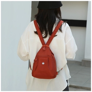 Detailed view of the bright orange nylon mini backpack with high-quality metal logo