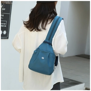 Detail of teal waterproof nylon chest bag with metal logo and top zipper closure