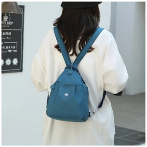 Outdoor shot showing back view of dark blue nylon mini backpack on model for daily use