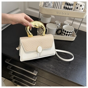 Detail of white leather and straw patchwork handbag with a unique gold metal handle