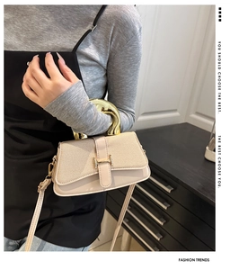 Detail view of stylish beige square handbag with unique oversized gold semicircular handle